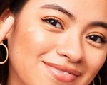 Smiling woman applying cream to her cheekbones